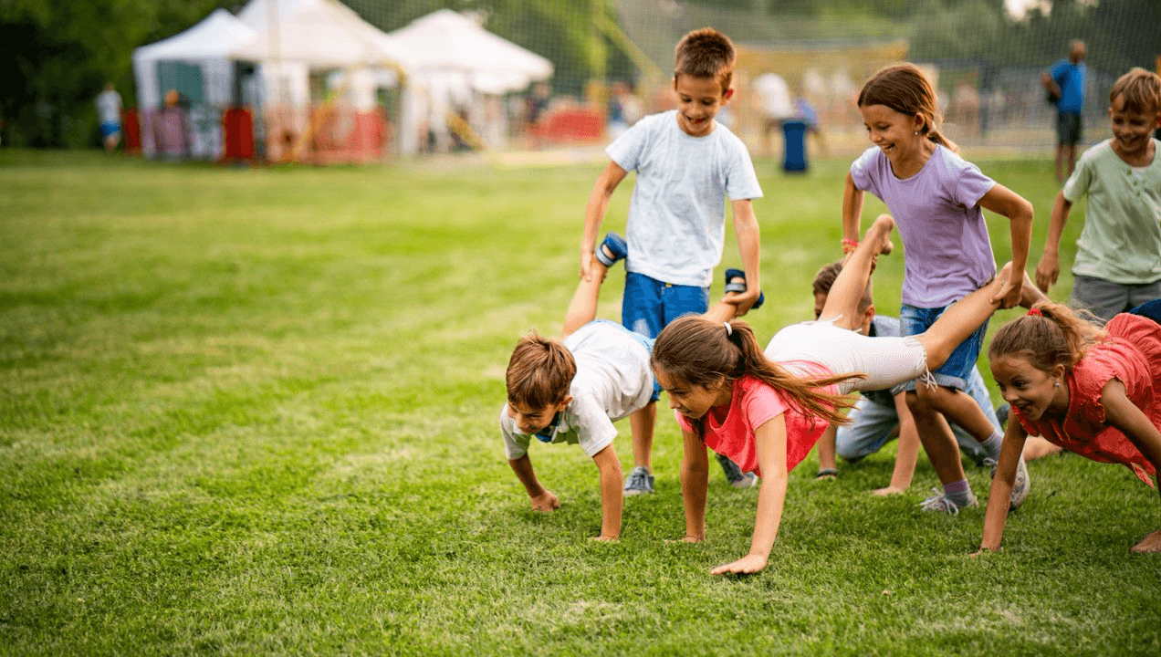 A group of children doing push ups on a grassy field.