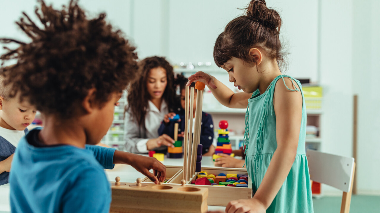 A group of children playing with wooden blocks in a classroom.