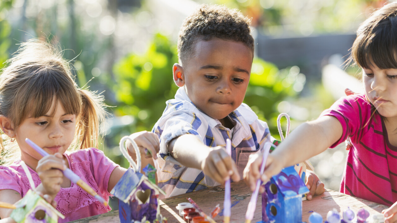 A group of children playing with toys in a garden.